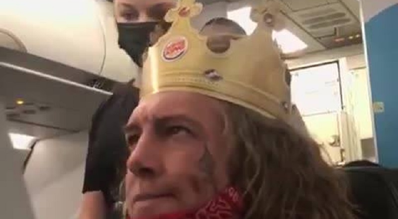 A white man, on an airplane, wearing a Burger King crown, was screaming racial slurs. The man kept screaming "n*gger b*tch," and repeatedly said "n*gger." When the flight attendant asked him to calm down, the man accused the woman of putting her stuff in his seat, and then accused her of kneeing him in the stomach.